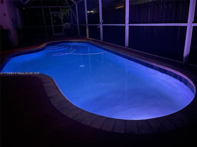 view of swimming pool featuring glass enclosure