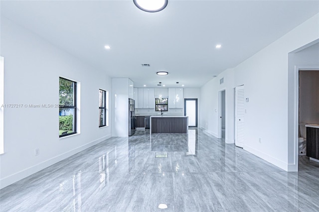 unfurnished living room with visible vents, recessed lighting, marble finish floor, and baseboards