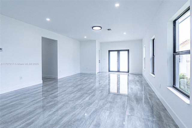 spare room featuring visible vents, plenty of natural light, and baseboards