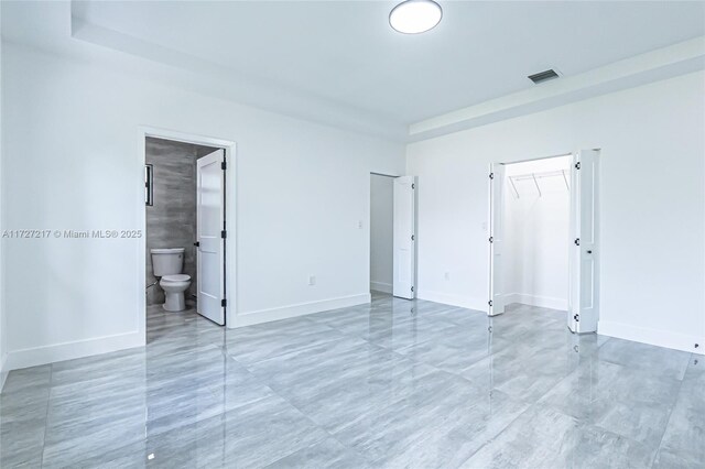 unfurnished bedroom featuring baseboards, visible vents, and ensuite bathroom