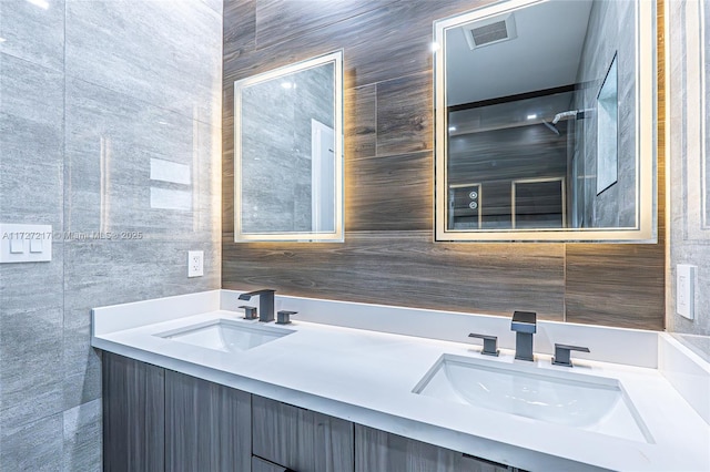 full bathroom with double vanity, tile walls, and a sink