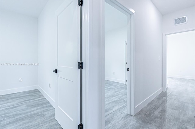 hall featuring wood finished floors, baseboards, and visible vents