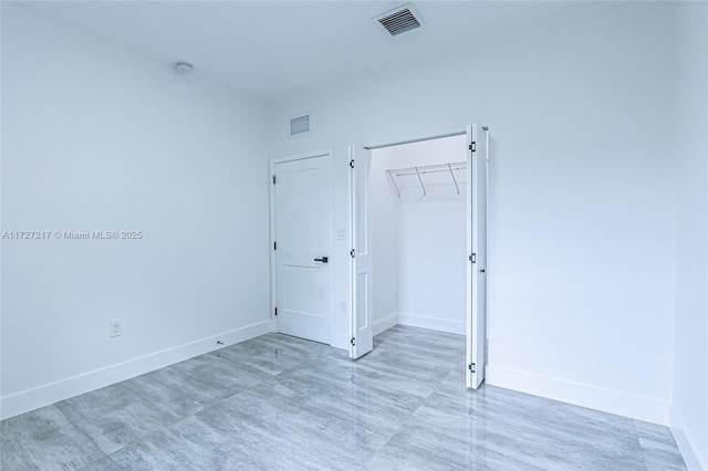 unfurnished bedroom with baseboards, visible vents, and a closet