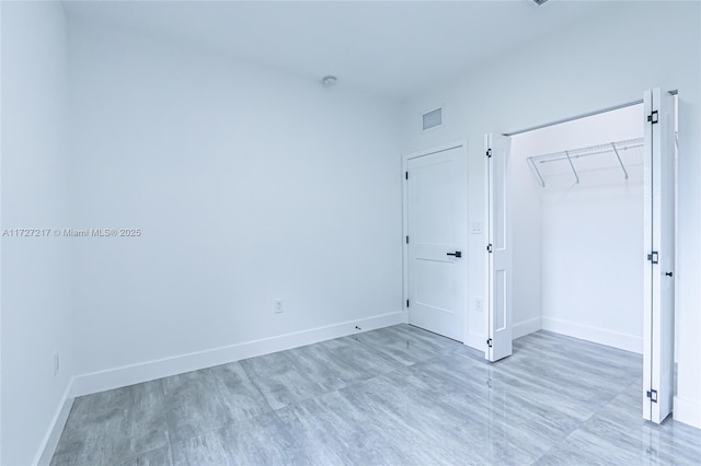 unfurnished bedroom with baseboards, visible vents, and a closet