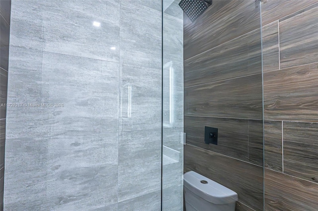 bathroom with a tile shower and toilet