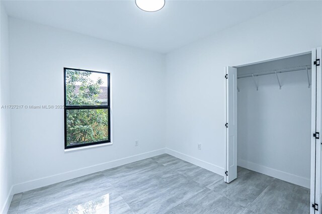 unfurnished bedroom with a closet and baseboards