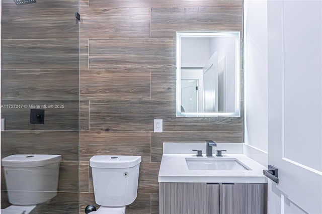 half bath featuring vanity, tile walls, and toilet