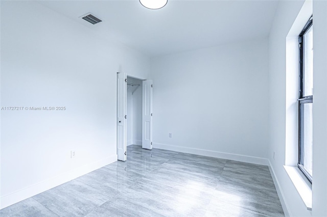 unfurnished room featuring a wealth of natural light, visible vents, and baseboards