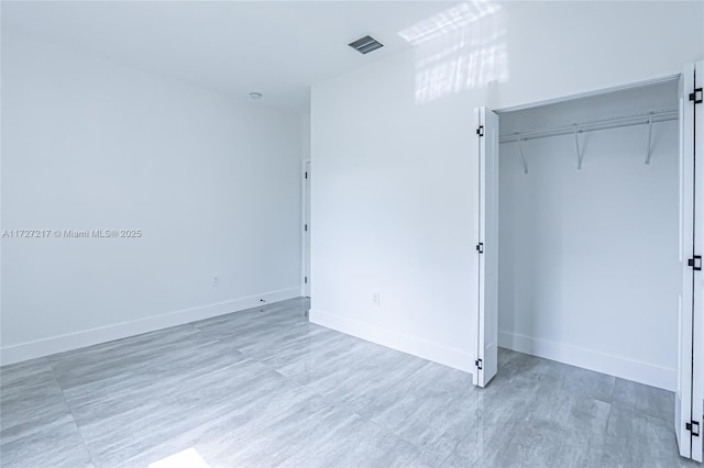 unfurnished bedroom with visible vents, baseboards, and a closet