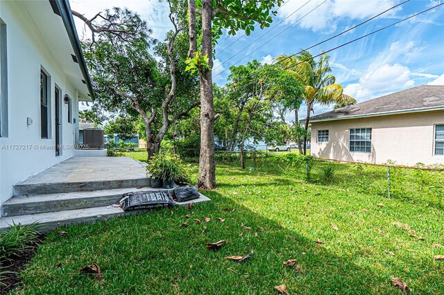 view of yard featuring central AC and fence