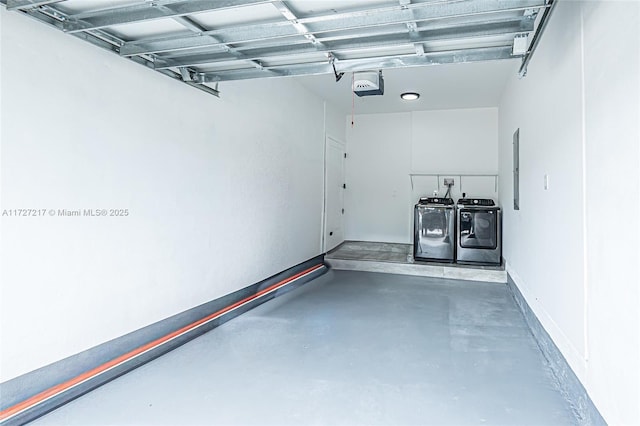 garage with washing machine and dryer, a garage door opener, and baseboards