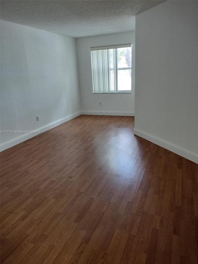 empty room featuring a textured ceiling and dark hardwood / wood-style flooring