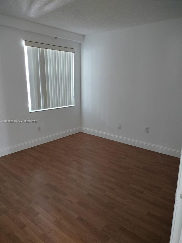 empty room with a textured ceiling and dark hardwood / wood-style floors