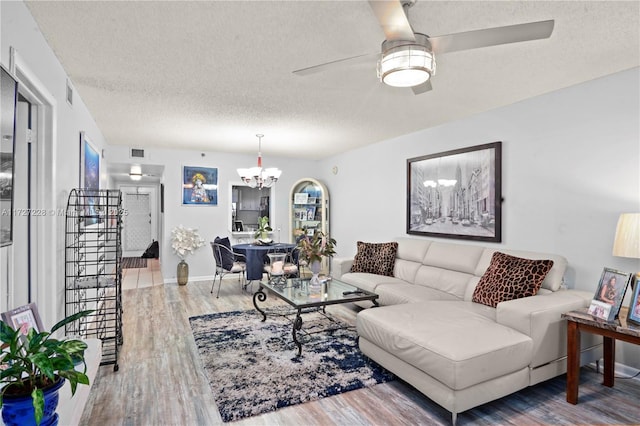 living room featuring ceiling fan with notable chandelier, a textured ceiling, and hardwood / wood-style floors