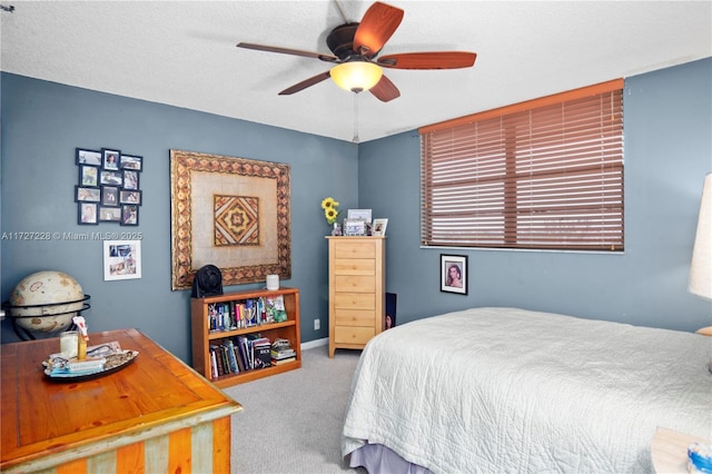 carpeted bedroom with ceiling fan and a textured ceiling