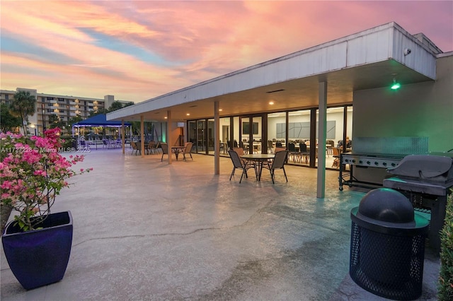 patio terrace at dusk featuring a grill