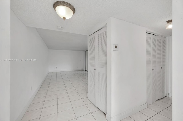 corridor featuring a textured ceiling and light tile patterned floors