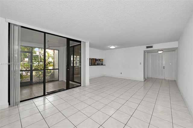 spare room featuring a textured ceiling, light tile patterned floors, and a wall of windows