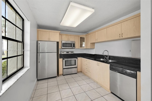 kitchen featuring light brown cabinetry, appliances with stainless steel finishes, sink, and a textured ceiling