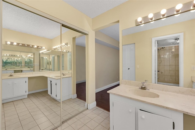 bathroom with vanity, tile patterned flooring, a textured ceiling, and a tile shower