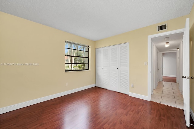 unfurnished bedroom with hardwood / wood-style flooring, a textured ceiling, and a closet