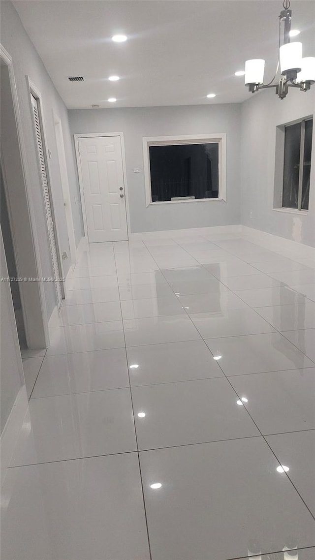 hall with light tile patterned floors and a chandelier