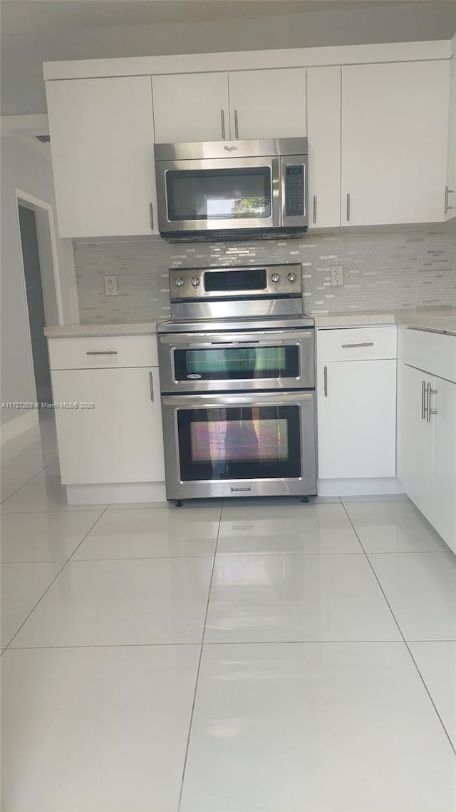 kitchen featuring white cabinets, light tile patterned flooring, and stainless steel appliances