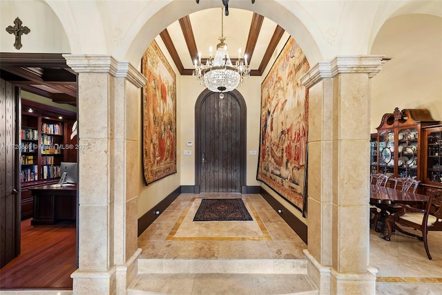 hallway with an inviting chandelier, ornamental molding, and decorative columns