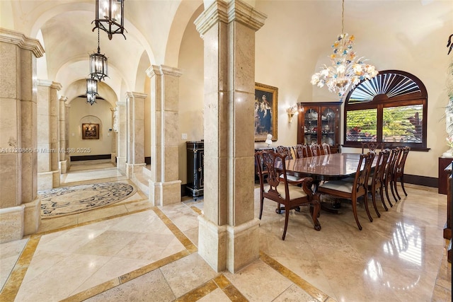 dining space featuring ornate columns, a chandelier, a towering ceiling, and french doors