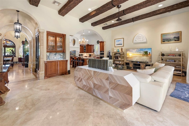 living room featuring a wealth of natural light, a chandelier, and beamed ceiling