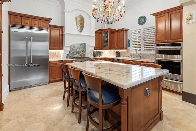 kitchen featuring appliances with stainless steel finishes, a notable chandelier, hanging light fixtures, a kitchen island, and sink