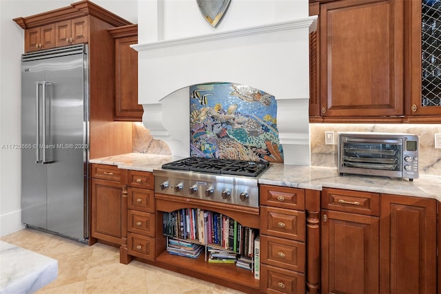 kitchen with light tile patterned flooring, appliances with stainless steel finishes, decorative backsplash, and light stone countertops