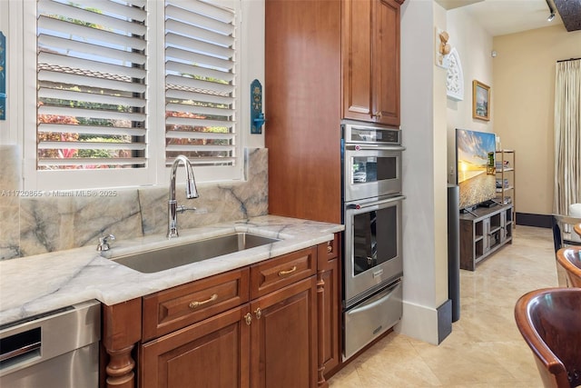 kitchen with appliances with stainless steel finishes, light stone counters, tasteful backsplash, and sink