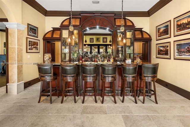 bar featuring crown molding, hanging light fixtures, and decorative columns