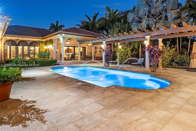 pool at dusk featuring pool water feature and a patio