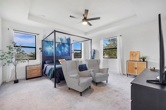 carpeted bedroom featuring ceiling fan and a tray ceiling