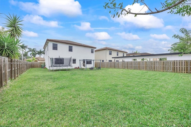 rear view of property featuring a yard and a trampoline