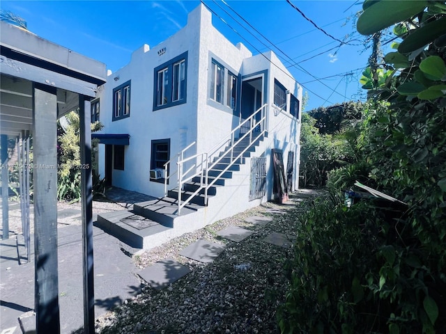 view of property exterior with cooling unit, stucco siding, and stairway
