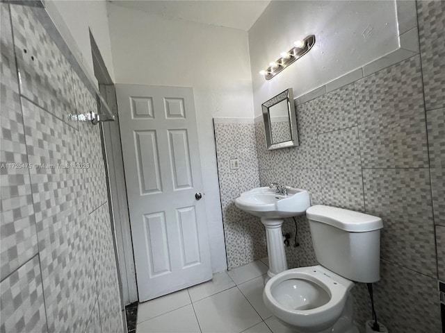 bathroom with tile walls, toilet, tile patterned flooring, and tiled shower