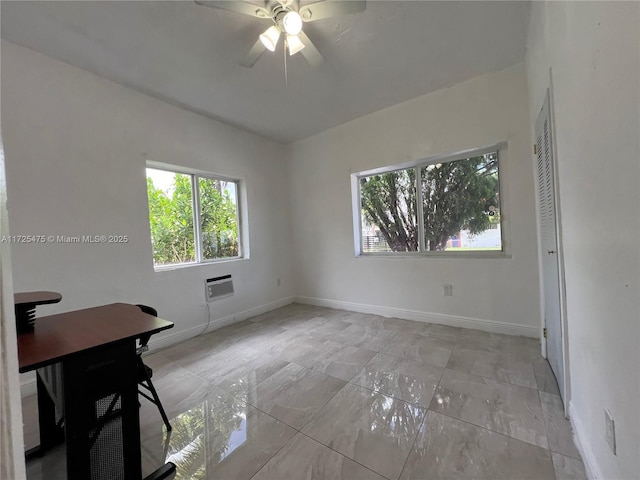 unfurnished room with ceiling fan and a wall unit AC