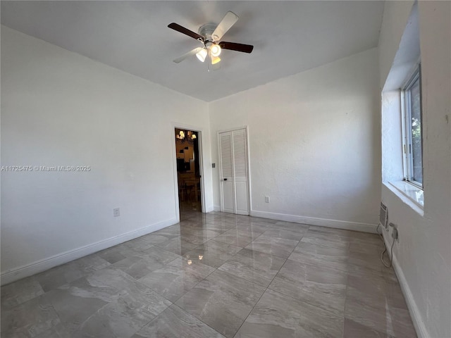spare room featuring a ceiling fan and baseboards