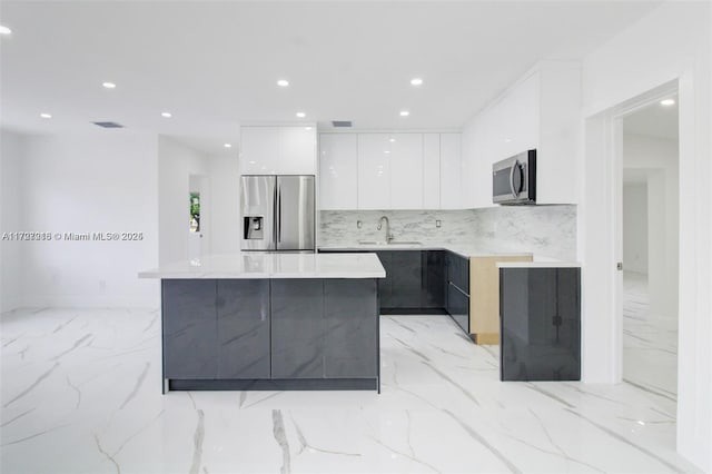 kitchen featuring tasteful backsplash, a center island, sink, appliances with stainless steel finishes, and white cabinets