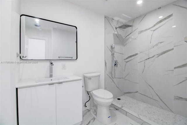 bathroom featuring toilet, vanity, and a tile shower