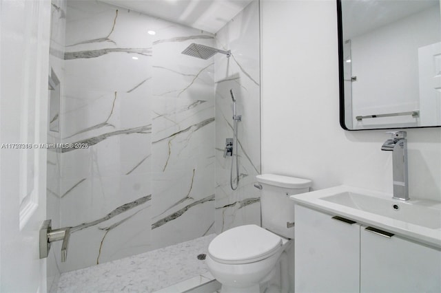 bathroom featuring toilet, a tile shower, and vanity