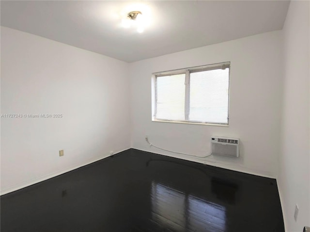 unfurnished room featuring an AC wall unit and hardwood / wood-style floors