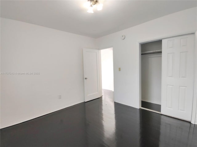 unfurnished bedroom with dark hardwood / wood-style floors and a closet