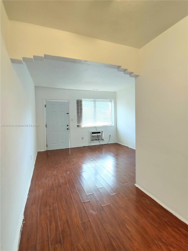 unfurnished living room featuring a wall mounted AC and dark wood-type flooring