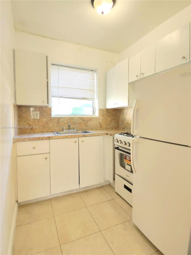 kitchen featuring white appliances, white cabinets, sink, backsplash, and light tile patterned flooring