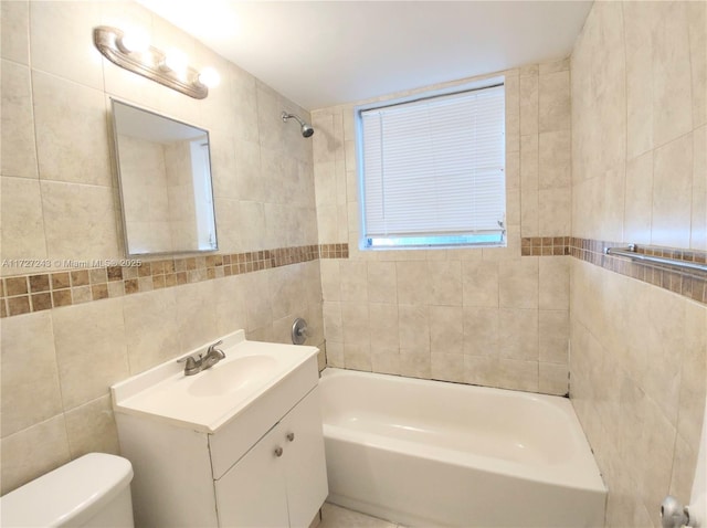 full bathroom with toilet, tile walls, vanity, and tiled shower / bath combo