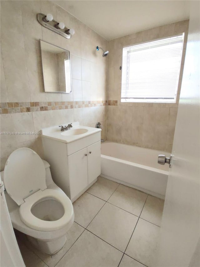 full bathroom featuring tiled shower / bath combo, tile patterned floors, vanity, tile walls, and toilet